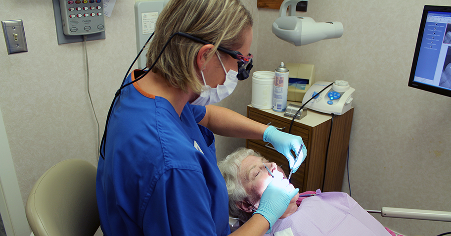 Dental assistant cleaning woman's teeth at dentist office in Richfield, MN